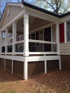 a white porch with red shutters on the front and side of a small house