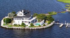 an aerial view of a large white house with a dock in the middle of it