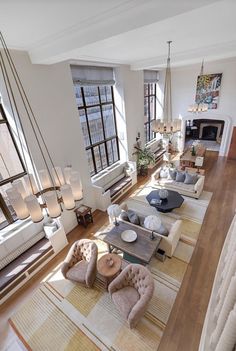 a living room filled with lots of furniture next to a fire place and large windows