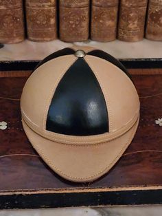 a leather baseball cap sitting on top of a wooden table next to bookshelves