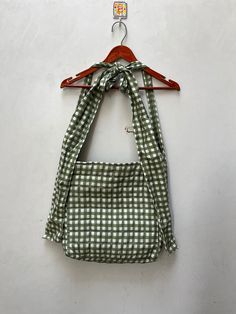 a green and white checkered bag hanging on a wall with a wooden hanger