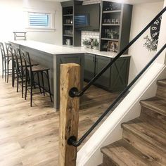 a kitchen with an island and bar in the center, next to stairs leading up to it