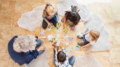 four children sitting on the floor playing with puzzle pieces