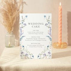 a wedding menu sitting on top of a table next to a vase and two candles