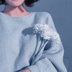 a woman wearing a sweater and holding a flower