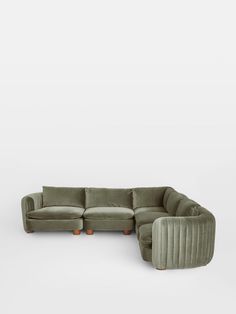 a green sectional couch with two chairs