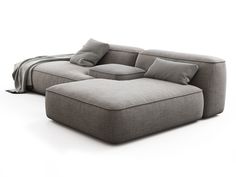 a large gray couch sitting on top of a white floor next to a pillow and blanket