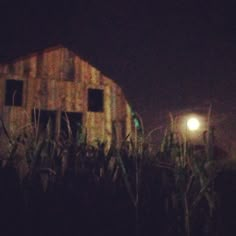 an old barn is lit up at night by the light of a street lamp in front of it