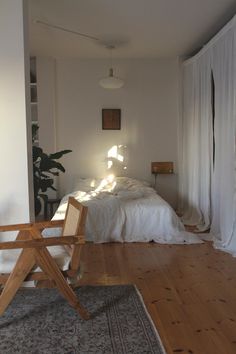 a bed sitting on top of a hard wood floor next to a white curtained wall