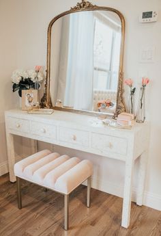 a white dressing table with a mirror and stool