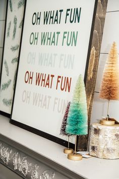 three christmas trees sitting on top of a mantle next to a sign that reads oh what fun oh what fun oh what fun oh what fun oh what fun oh what fun oh what fun