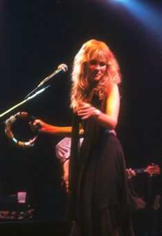 a woman standing in front of a microphone on stage