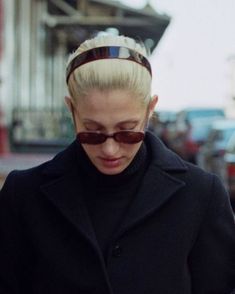 a woman with blonde hair and sunglasses looking at her cell phone while walking down the street