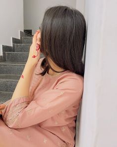 a woman is sitting on the stairs with her hand near her face