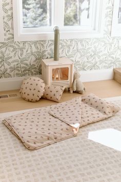 a teddy bear is sitting on the floor next to a blanket and pillow in front of a window