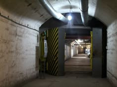 an underground tunnel with yellow and black striped barriers on both sides, leading to the exit