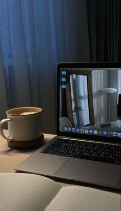 an open laptop computer sitting on top of a desk next to a cup of coffee