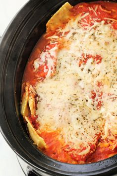 a crock pot filled with lasagna sauce and parmesan cheese on top