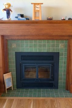 a fireplace with green tile and wooden mantle