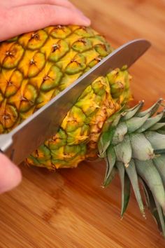 a person cutting up a pineapple with a knife