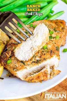 a white plate topped with meat and potatoes next to green beans on a wooden table