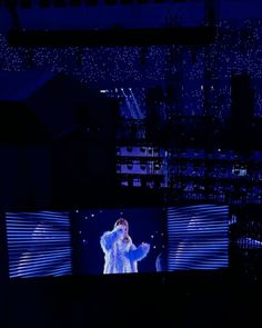 an image of a person on a stage with lights in the background and buildings lit up at night