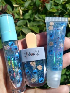 someone is holding two small bottles with blue glitters on them and one has a toothbrush in it