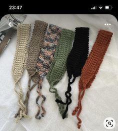 five crocheted headbands laid out on top of a white towel next to a pair of scissors