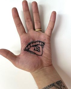 a person's hand with a small tattoo on the middle of their left palm