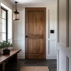 an entryway with a wooden door, bench and potted plant on the side