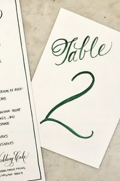 the table numbers are green and black on white paper, with handwritten calligraphy