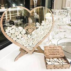 a heart shaped mirror sitting on top of a table next to some wine glasses and other items