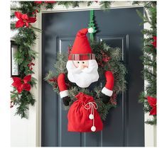 a christmas wreath with a santa clause hanging from it's side on a door