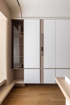 an empty room with wooden floors and white cabinets on the wall, along with a wood floor