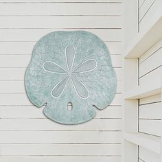 a white wall with a blue flower on it and a green plate hanging from the side