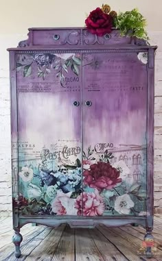 a purple painted cabinet with flowers on the front and bottom doors, sitting on a wooden floor