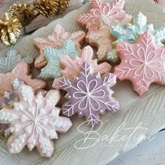 several decorated cookies on a plate with gold and pink decorations in the background, including snowflakes