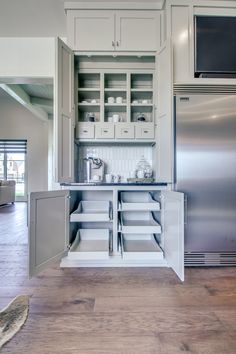 a kitchen with white cupboards and stainless steel refrigerator freezer combo in the center