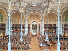 the inside of a library with many tables and chairs