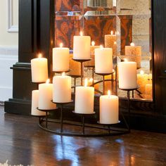 a bunch of lit candles sitting on top of a stand in front of a mirror