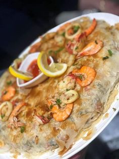 a person holding a plate of food with shrimp and other foods on it in their hands