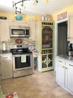 a kitchen with white cabinets and stainless steel stove top oven in the middle of it