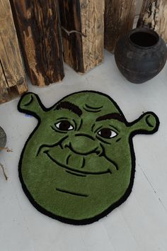 a green rug with an image of a cartoon character on the floor next to a potted plant