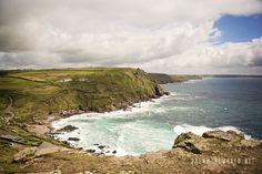 an ocean view from the top of a hill with waves crashing in to shore and green hills on either side