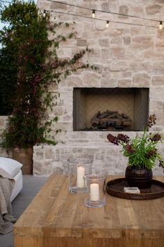 two candles are on a table in front of a fireplace