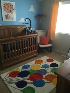 a baby's room with a crib, rocking chair and large rug on the floor