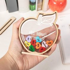 a person holding an apple shaped glass plaque with the names of their favorite fruits on it