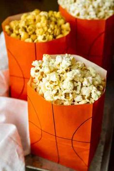 three orange bags filled with popcorn sitting on top of a table