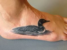 a small black and white duck on the bottom of a person's foot,