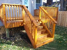 a wooden staircase next to a house in the yard with grass and leaves on the ground